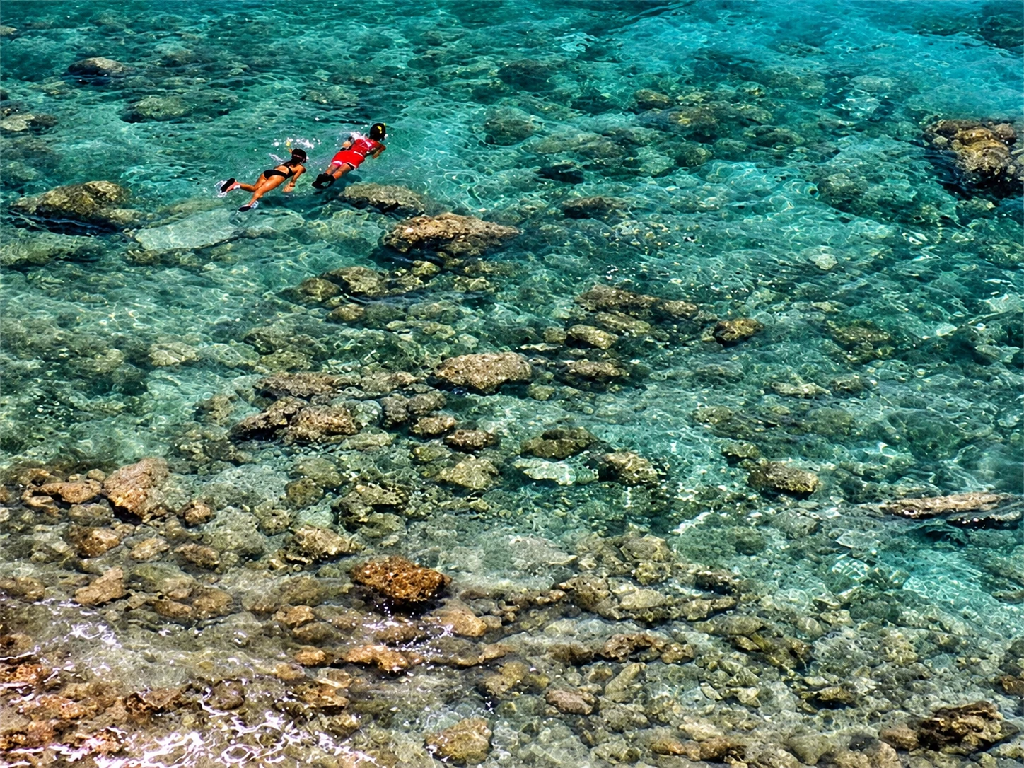 Пловцы над подводными камнями и кораллами в прозрачной воде у Канкуна, Мексика