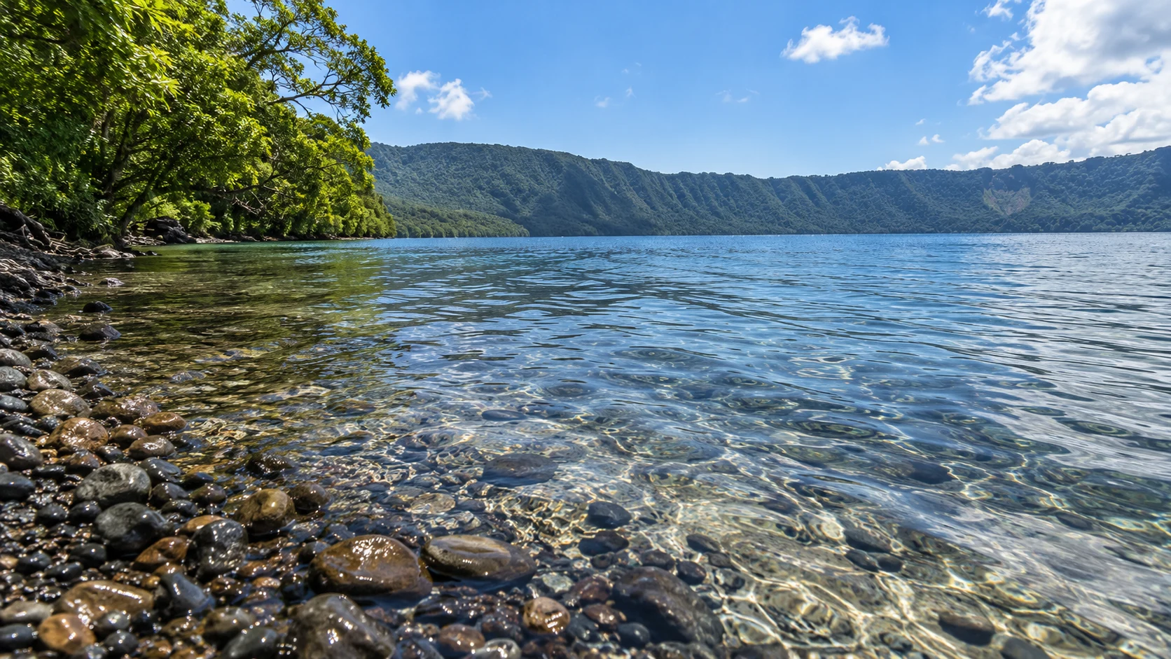 Прозрачная вода у галечного берега и лесистые склоны, Лагуна Апойо, Никарагуа
